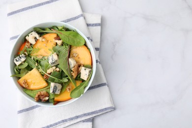 Tasty salad with persimmon, blue cheese and walnuts served on white marble table, top view. Space for text