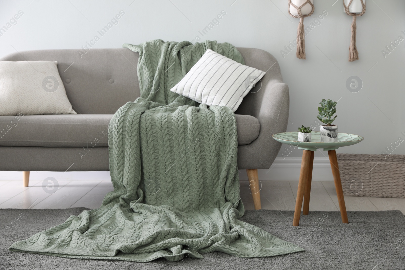 Photo of Soft knitted blanket on sofa in room. Home interior