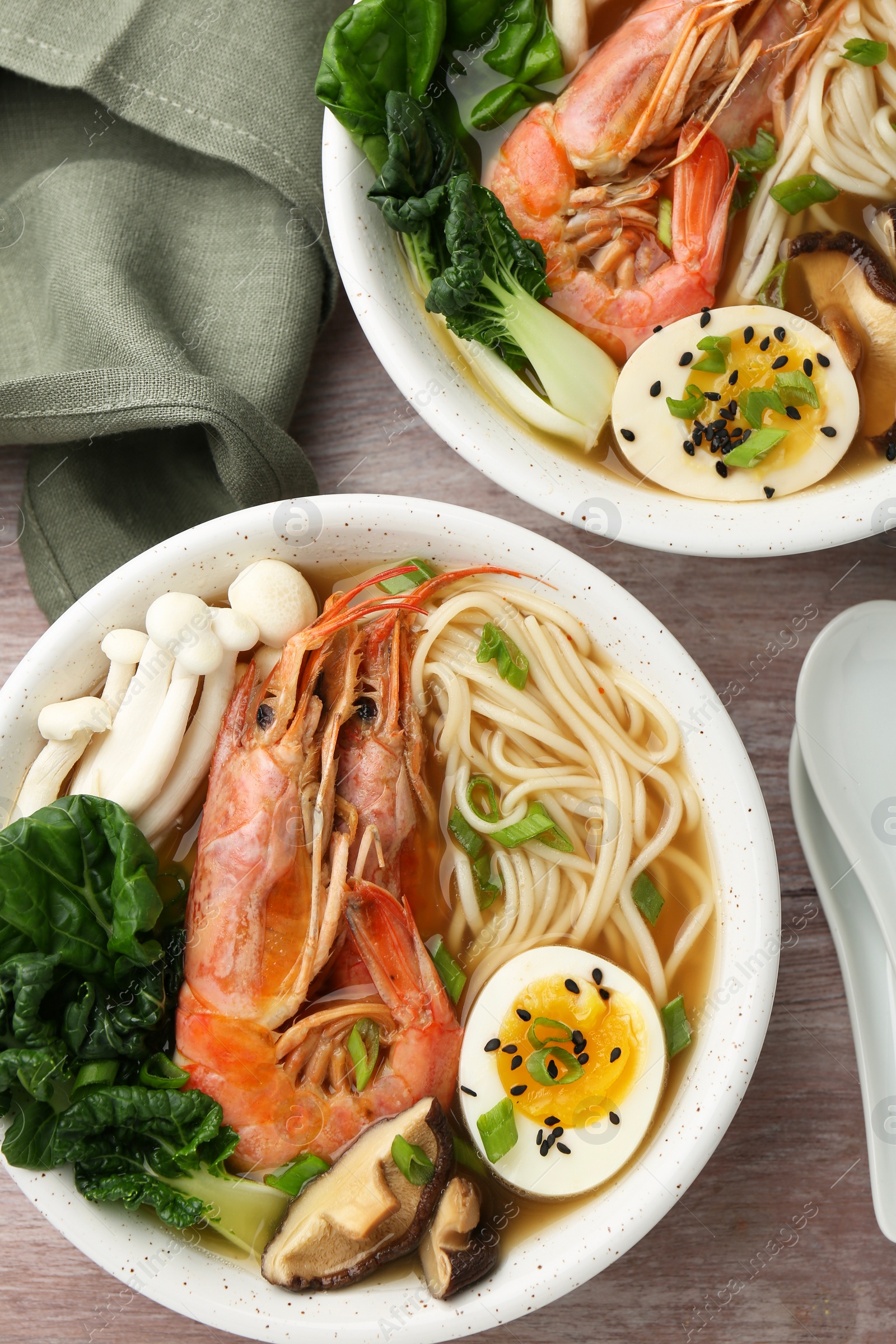 Photo of Delicious ramen with shrimps in bowls served on wooden table, flat lay. Noodle soup