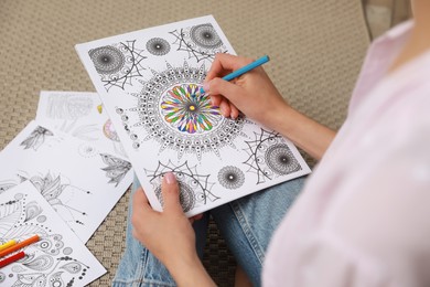 Young woman coloring antistress page on floor, closeup