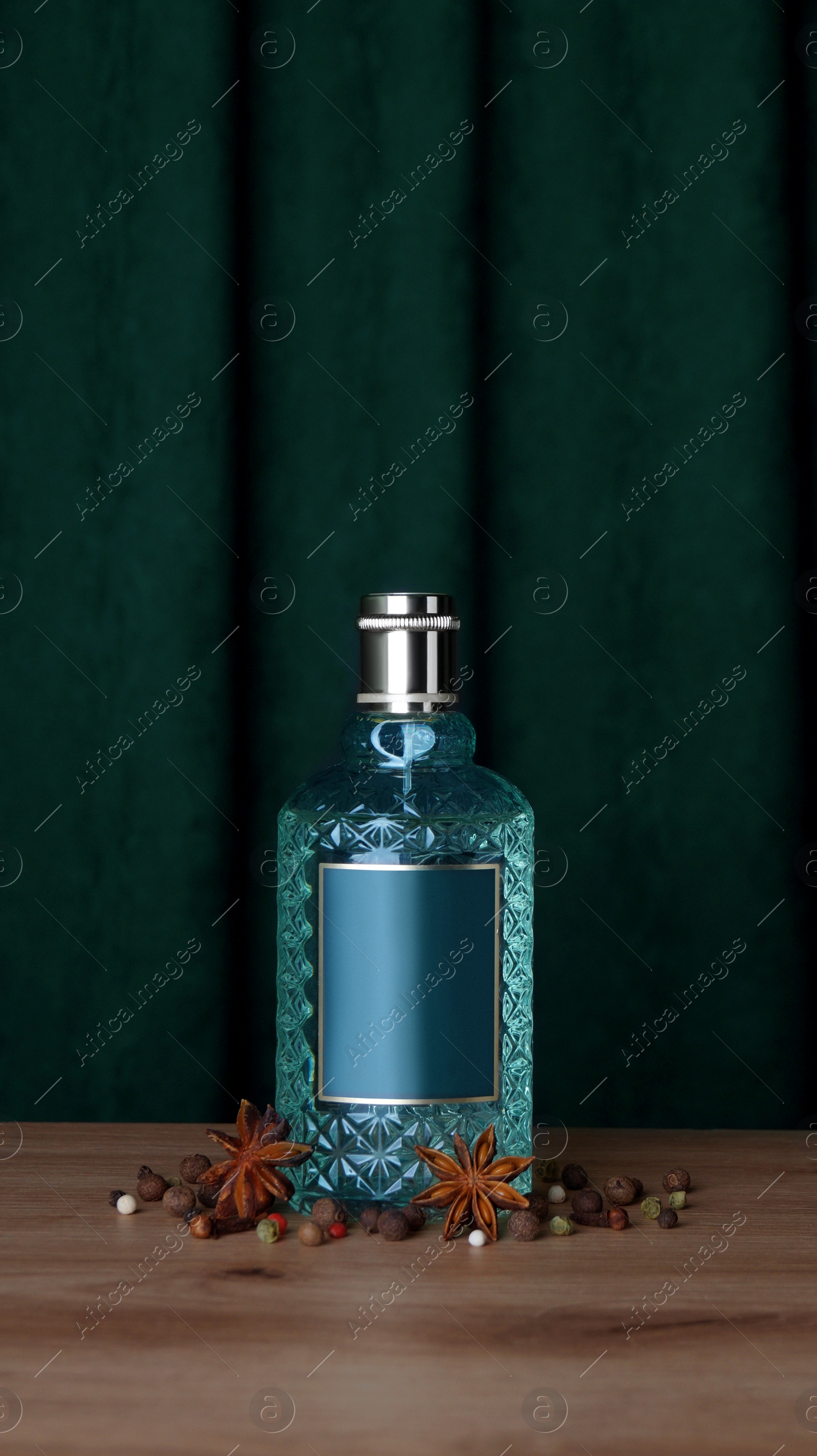 Photo of Bottle of perfume and different spices on wooden table