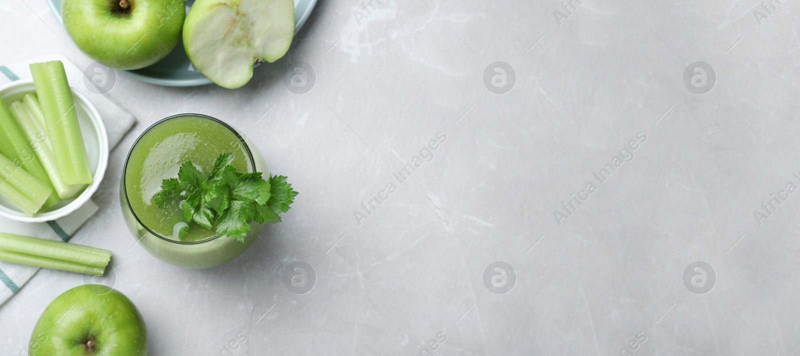 Photo of Flat lay composition with glass of fresh celery juice on light marble table. Space for text