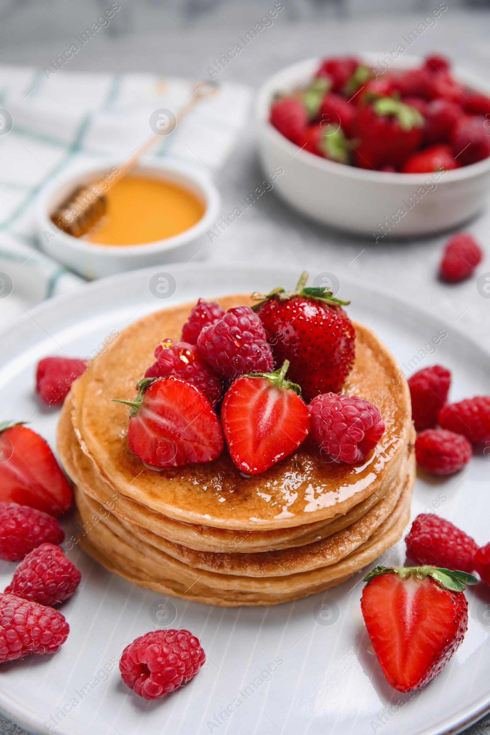 Photo of Tasty pancakes with fresh berries and honey on plate, closeup
