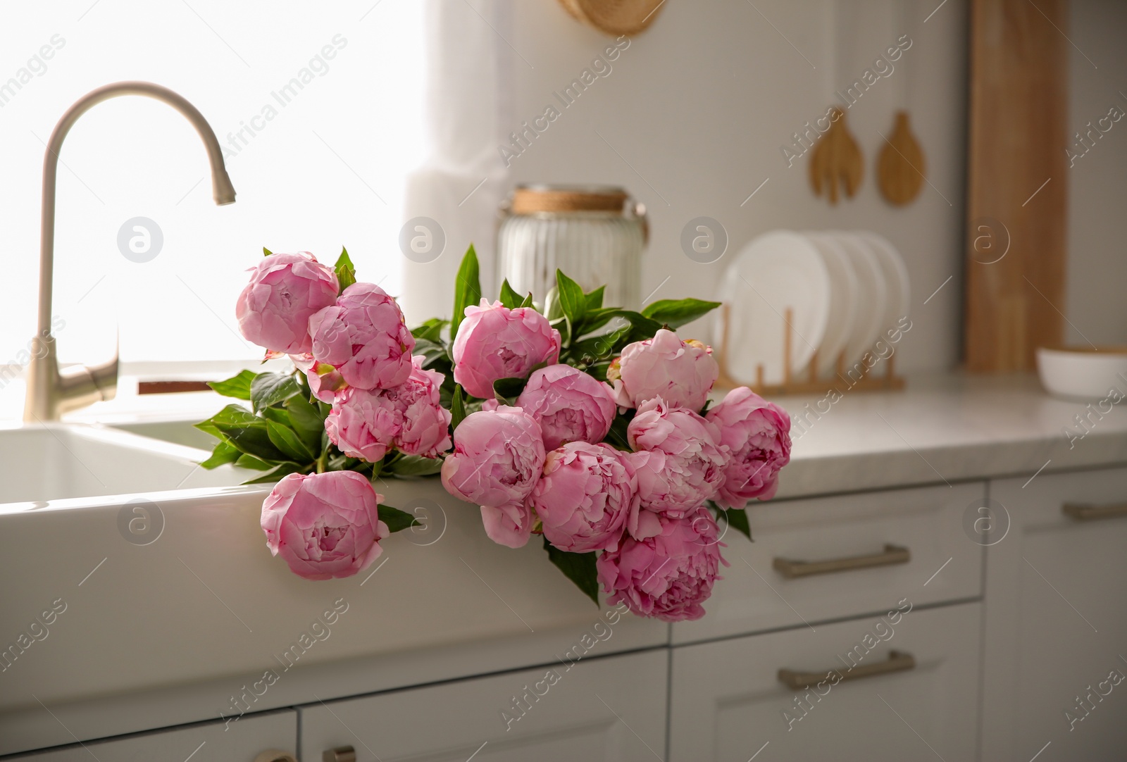 Photo of Bouquet of beautiful pink peonies in kitchen sink