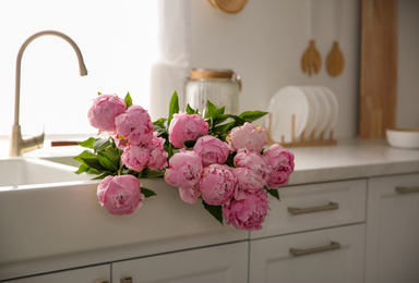 Photo of Bouquet of beautiful pink peonies in kitchen sink