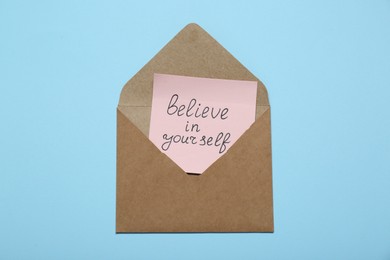 Photo of Envelope with message Believe In Yourself on light blue background, top view. Motivational quote