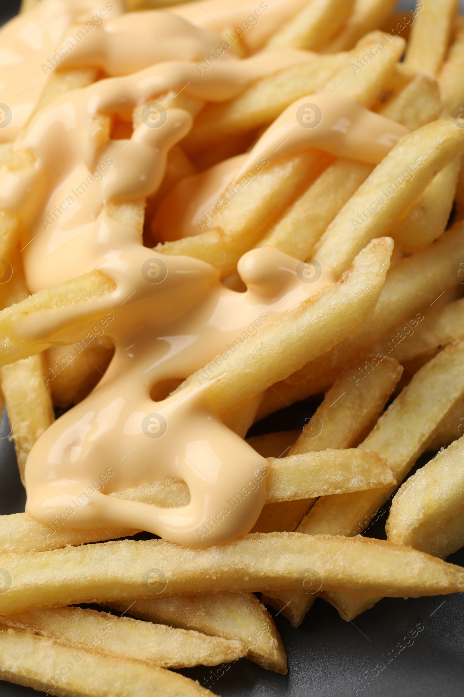 Photo of Delicious french fries with cheese sauce on plate, closeup