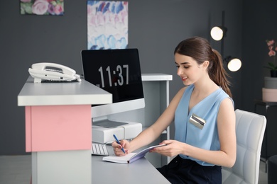Beauty salon receptionist with notebook at desk