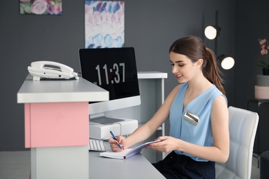 Photo of Beauty salon receptionist with notebook at desk