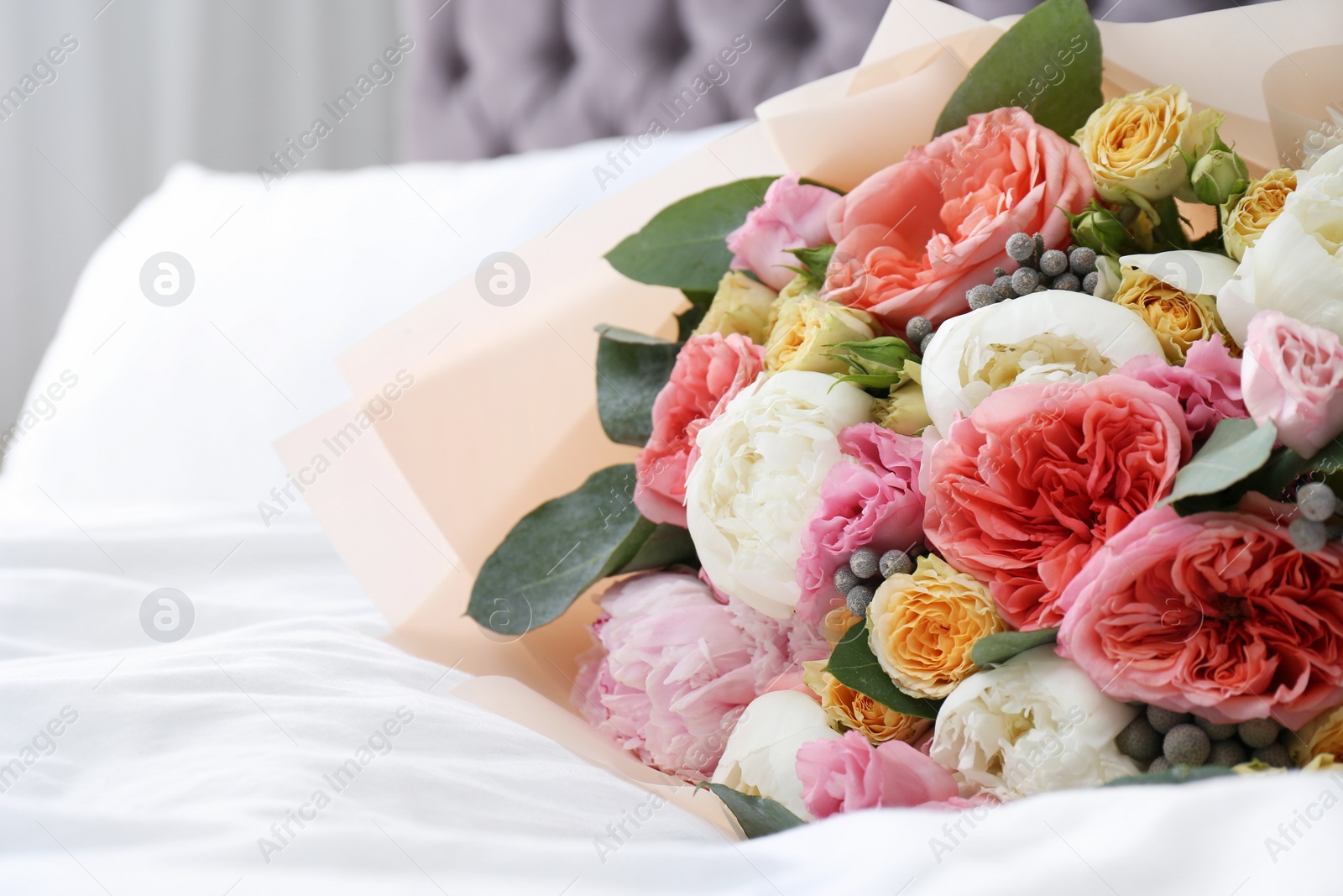 Photo of Beautiful flower bouquet on bed in light room. Space for text