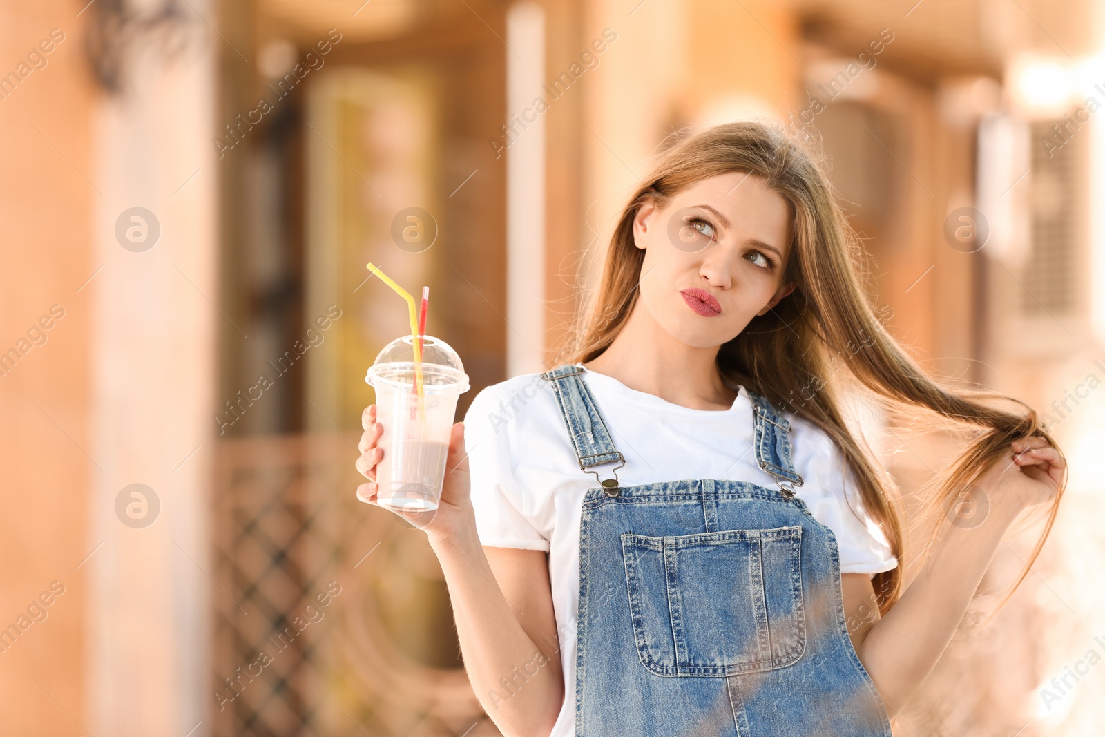 Photo of Young woman with cup of delicious milk shake outdoors