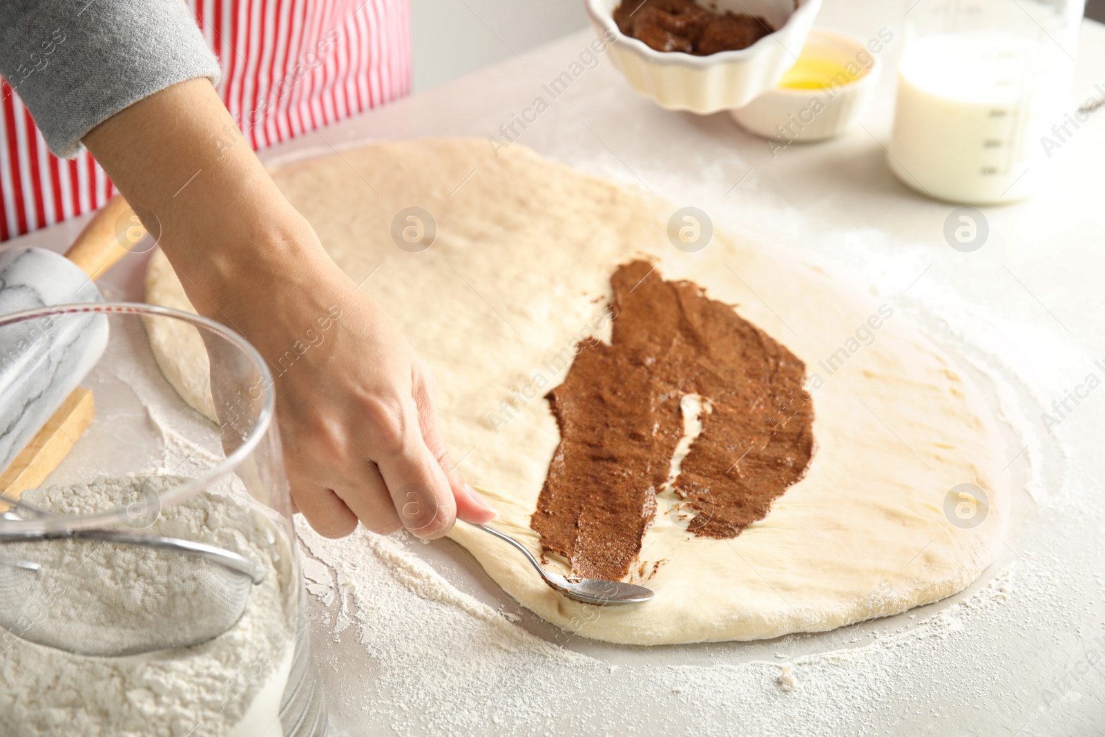 Photo of Woman making cinnamon rolls at table, closeup