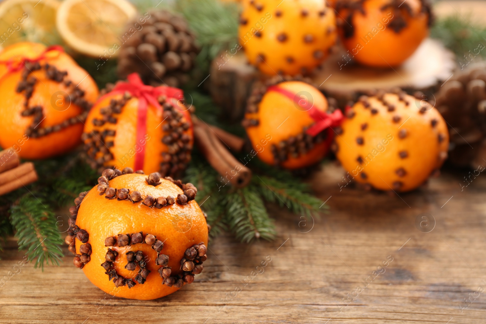 Photo of Pomander ball made of fresh tangerine and cloves on wooden table, space for text