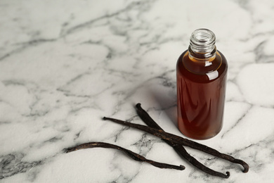 Photo of Aromatic homemade vanilla extract on marble table. Space for text