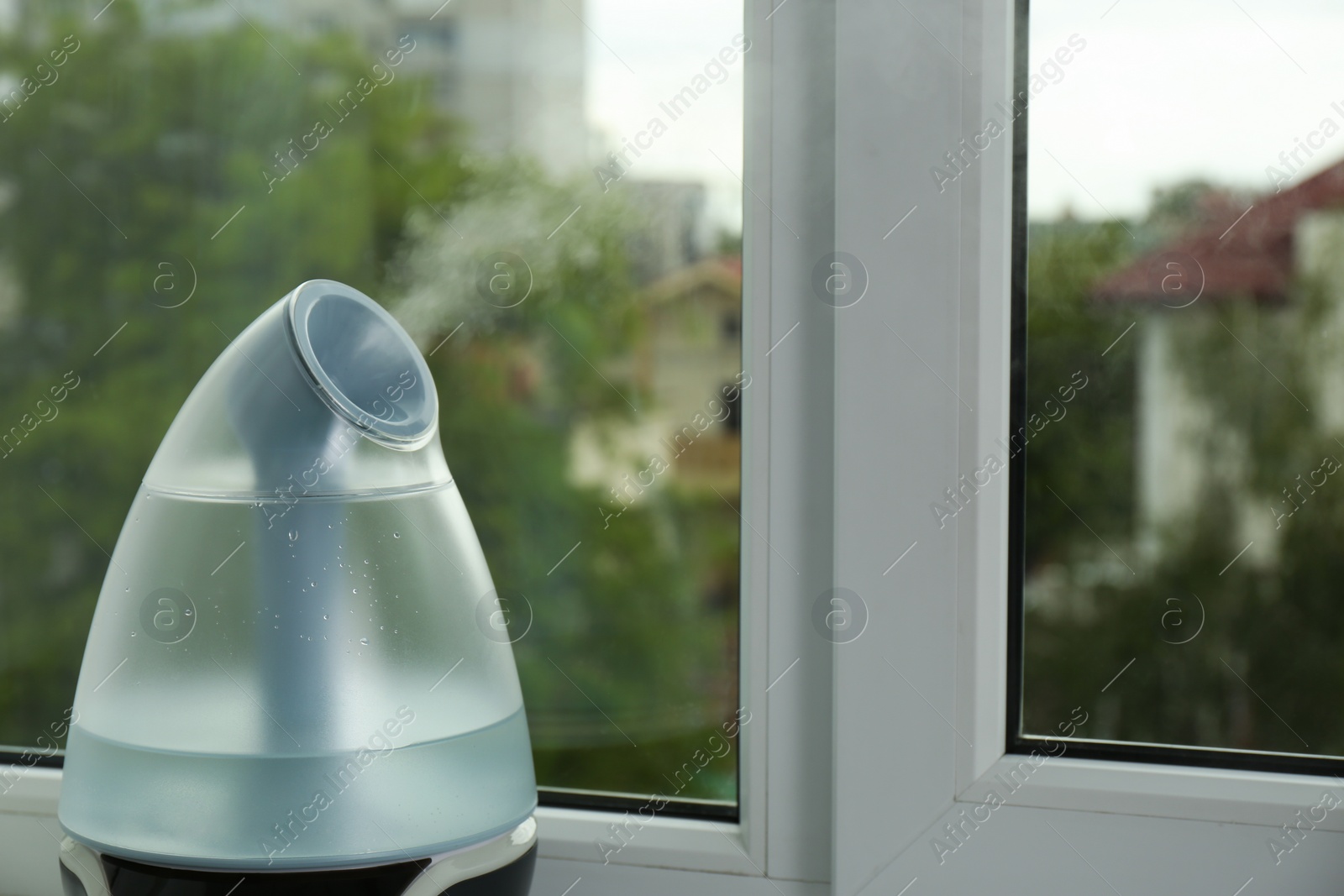Photo of Modern air humidifier near window indoors, closeup. Space for text