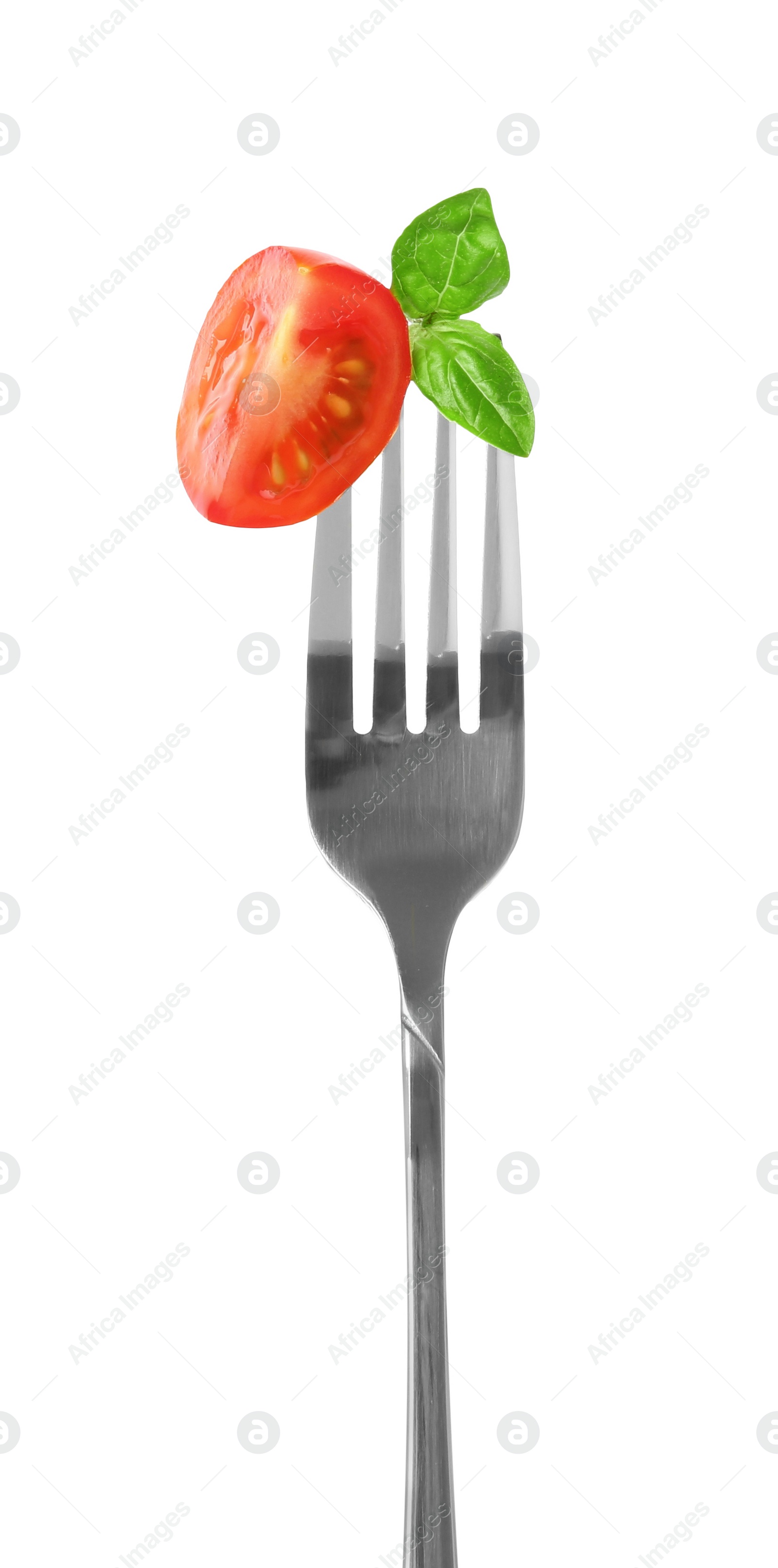 Photo of Fork with cut cherry tomato and basil isolated on white
