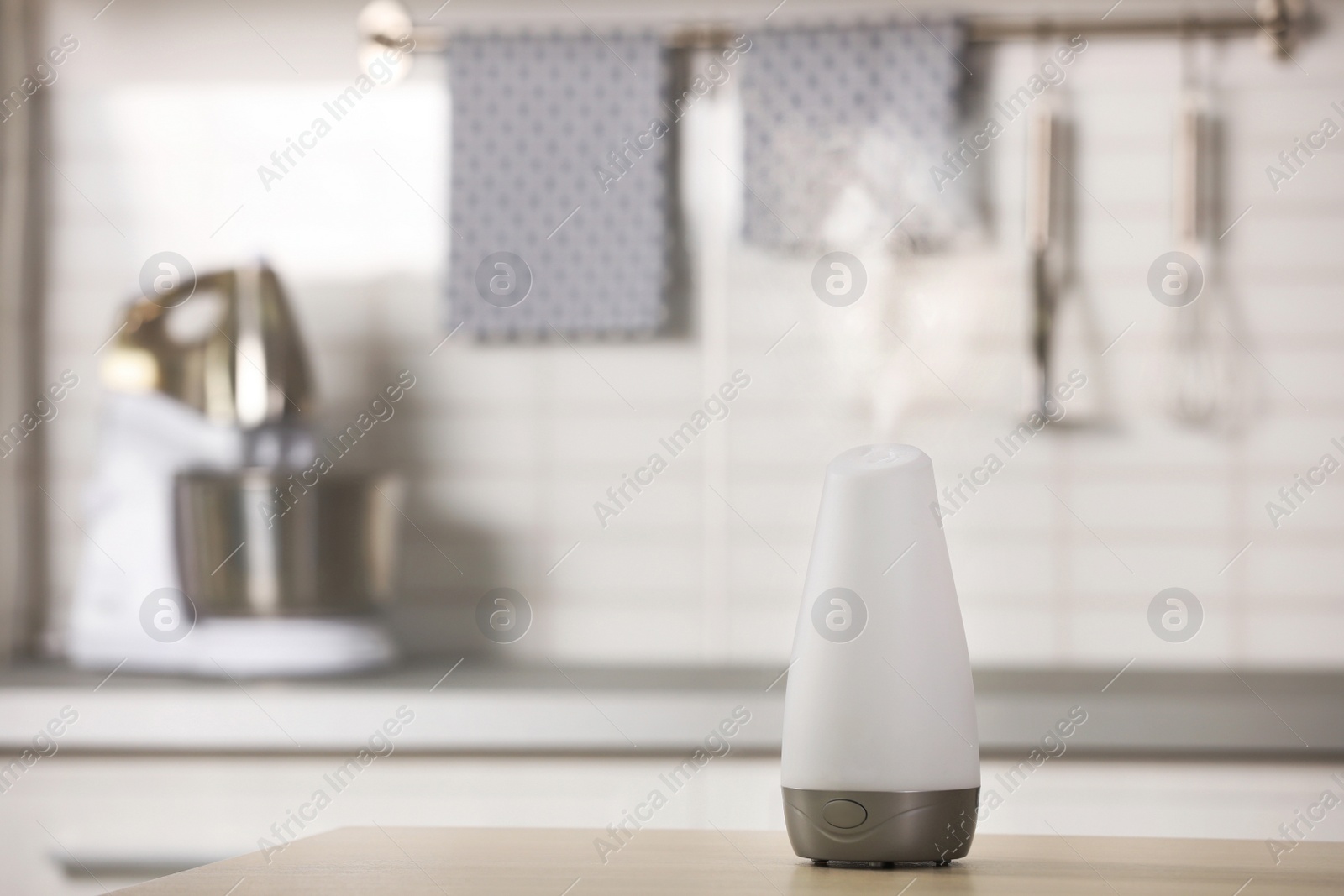 Photo of Modern essential oil diffuser on table indoors. Space for text