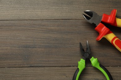 Photo of Pliers on wooden table, flat lay. Space for text