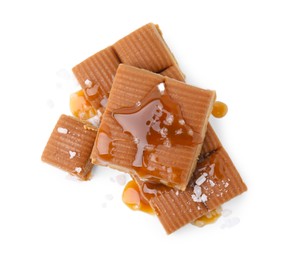 Photo of Yummy caramel candies and sea salt isolated on white, top view