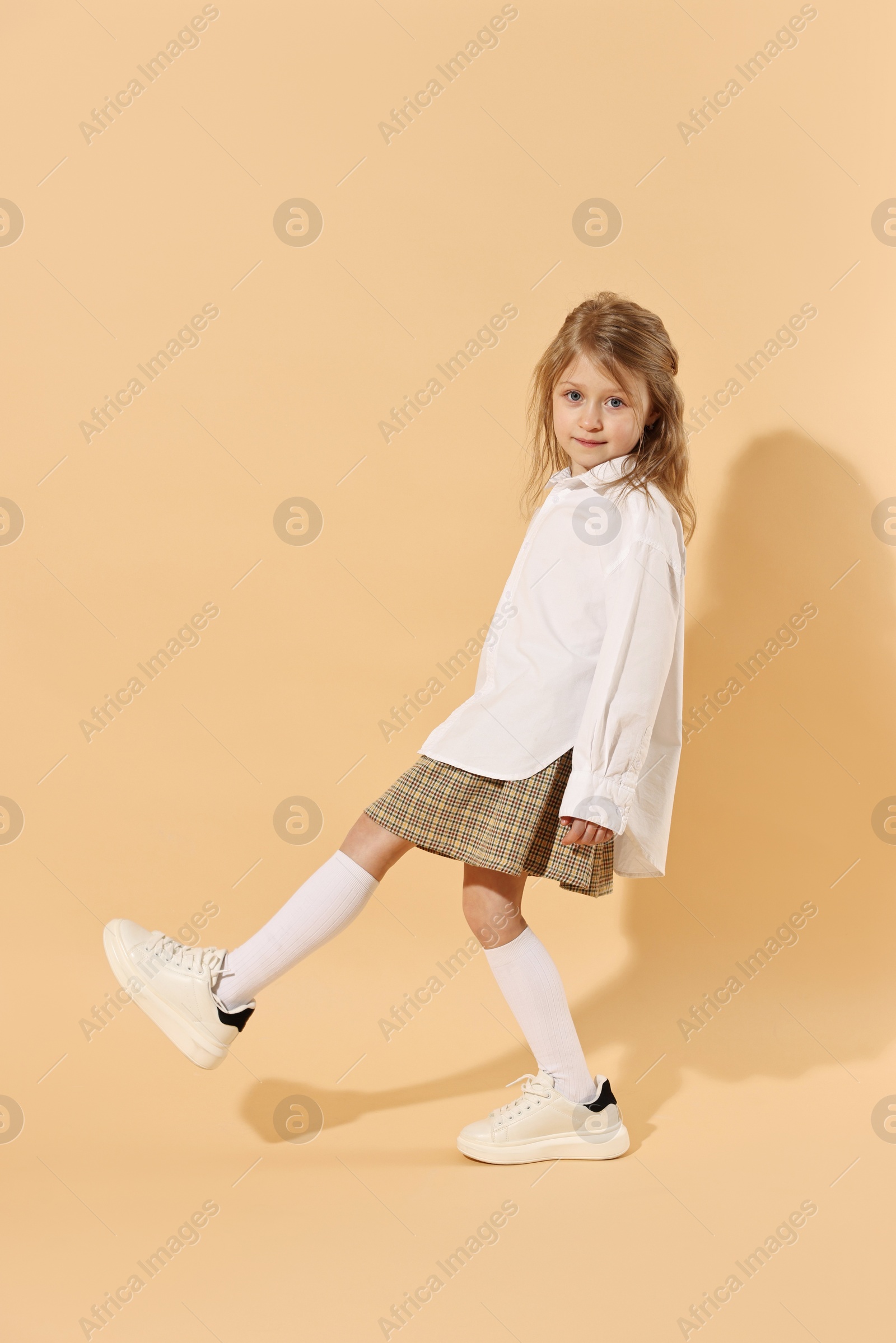 Photo of Fashion concept. Stylish girl on pale orange background