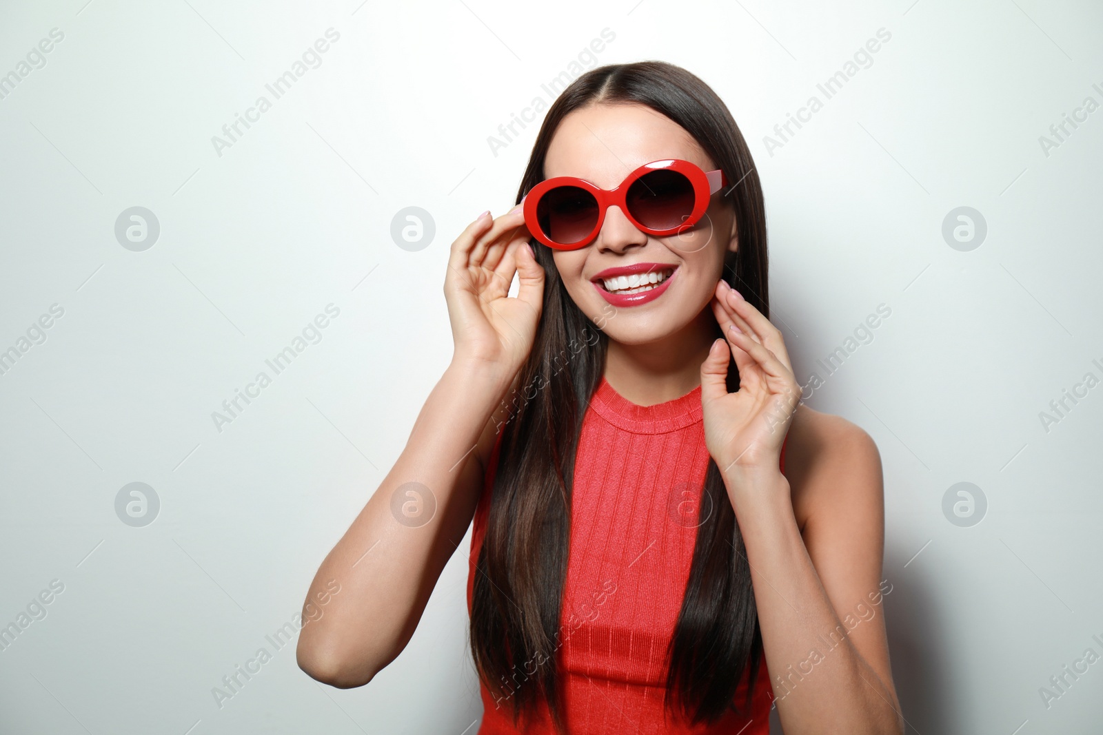 Photo of Beautiful woman in stylish sunglasses on light background