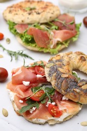 Tasty bagel sandwiches on white tiled table, closeup