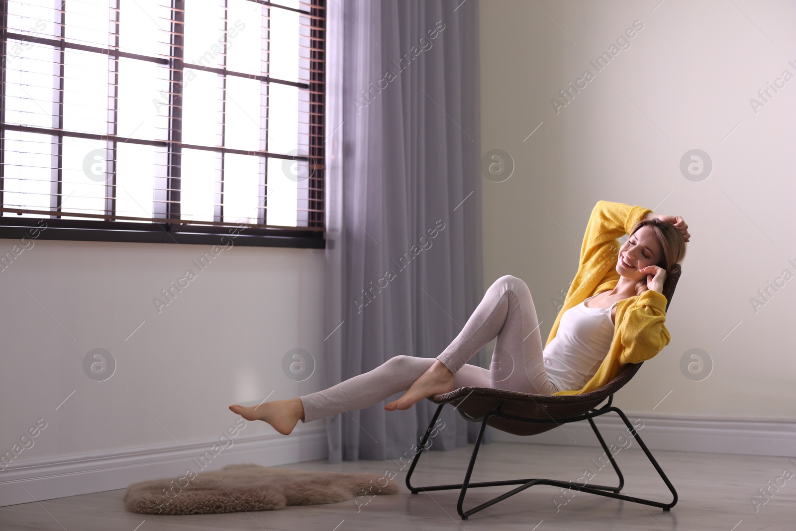 Photo of Young woman relaxing near window with blinds at home. Space for text