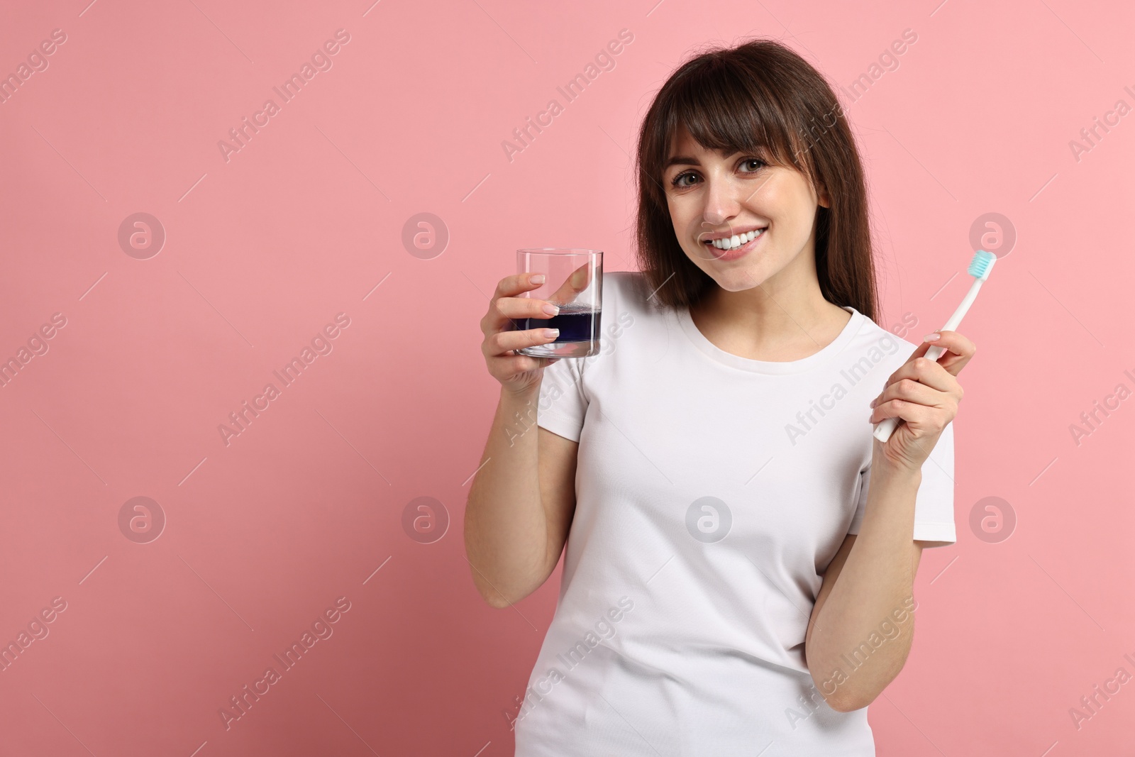 Photo of Young woman with mouthwash and toothbrush on pink background, space for text