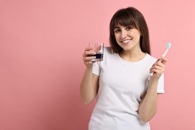 Photo of Young woman with mouthwash and toothbrush on pink background, space for text