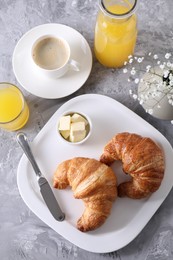 Photo of Tasty breakfast. Fresh croissants, coffee, juice and butter on grey table, flat lay