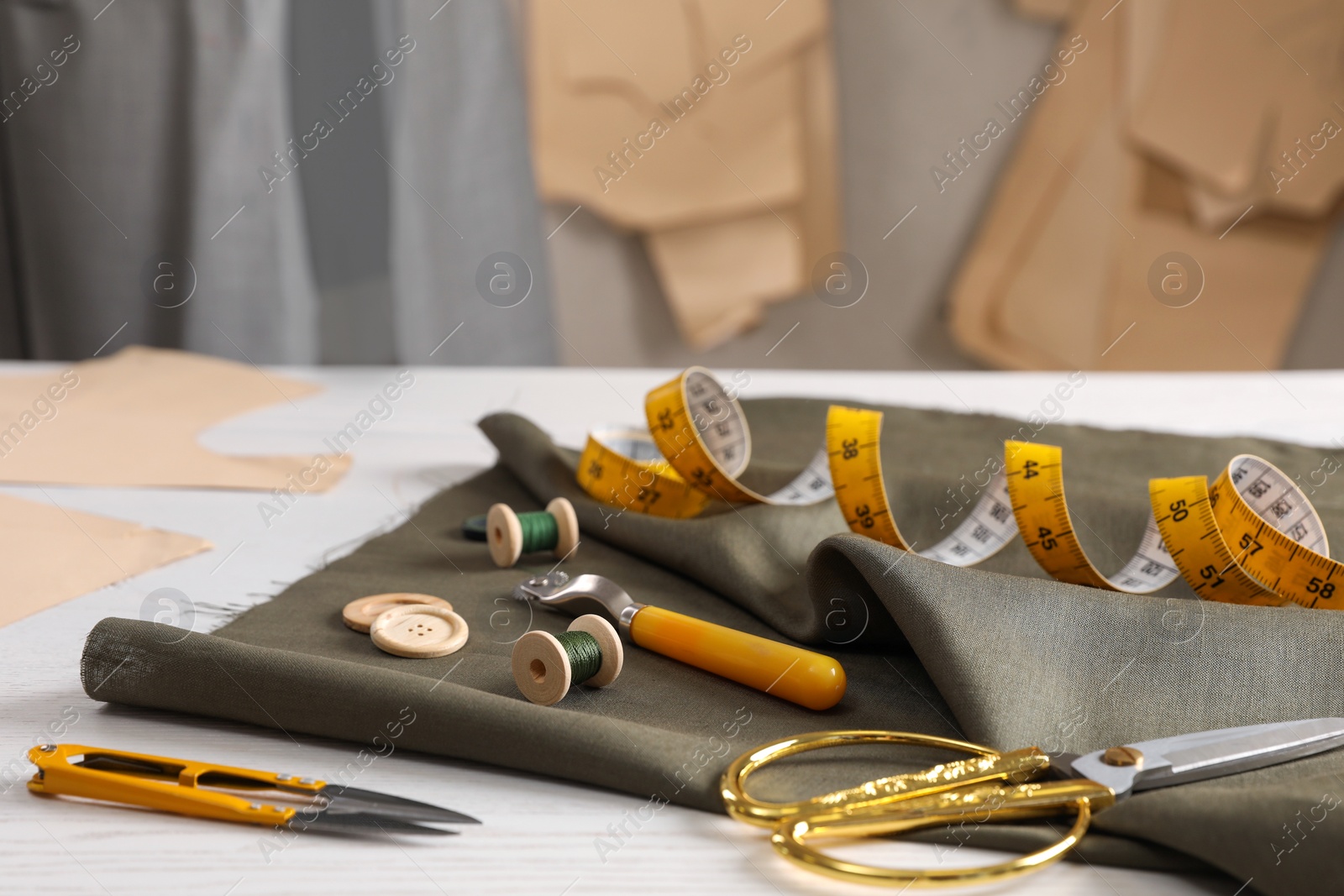 Photo of Set of sewing supplies and accessories with fabric on white wooden table indoors