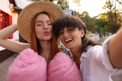 Happy friends with cotton candies taking selfie outdoors