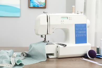 Photo of White sewing machine and cloth on wooden table indoors