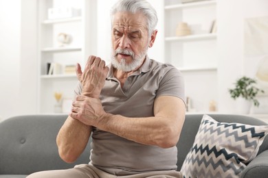Arthritis symptoms. Man suffering from pain in wrist at home