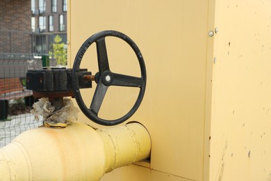 Black flywheel on yellow gas pipe outdoors