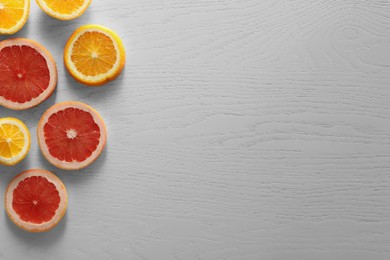 Food photography. Cut fresh citrus fruits on white wooden table, flat lay with space for text