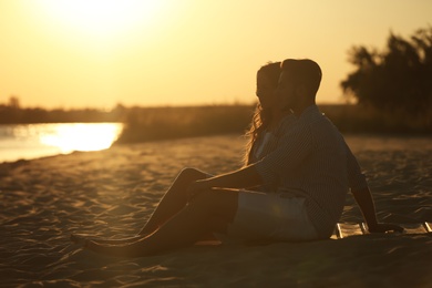 Happy young couple resting together on beach at sunset