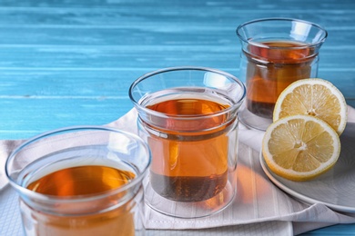 Plates with glasses of hot tea and lemon on blue wooden table