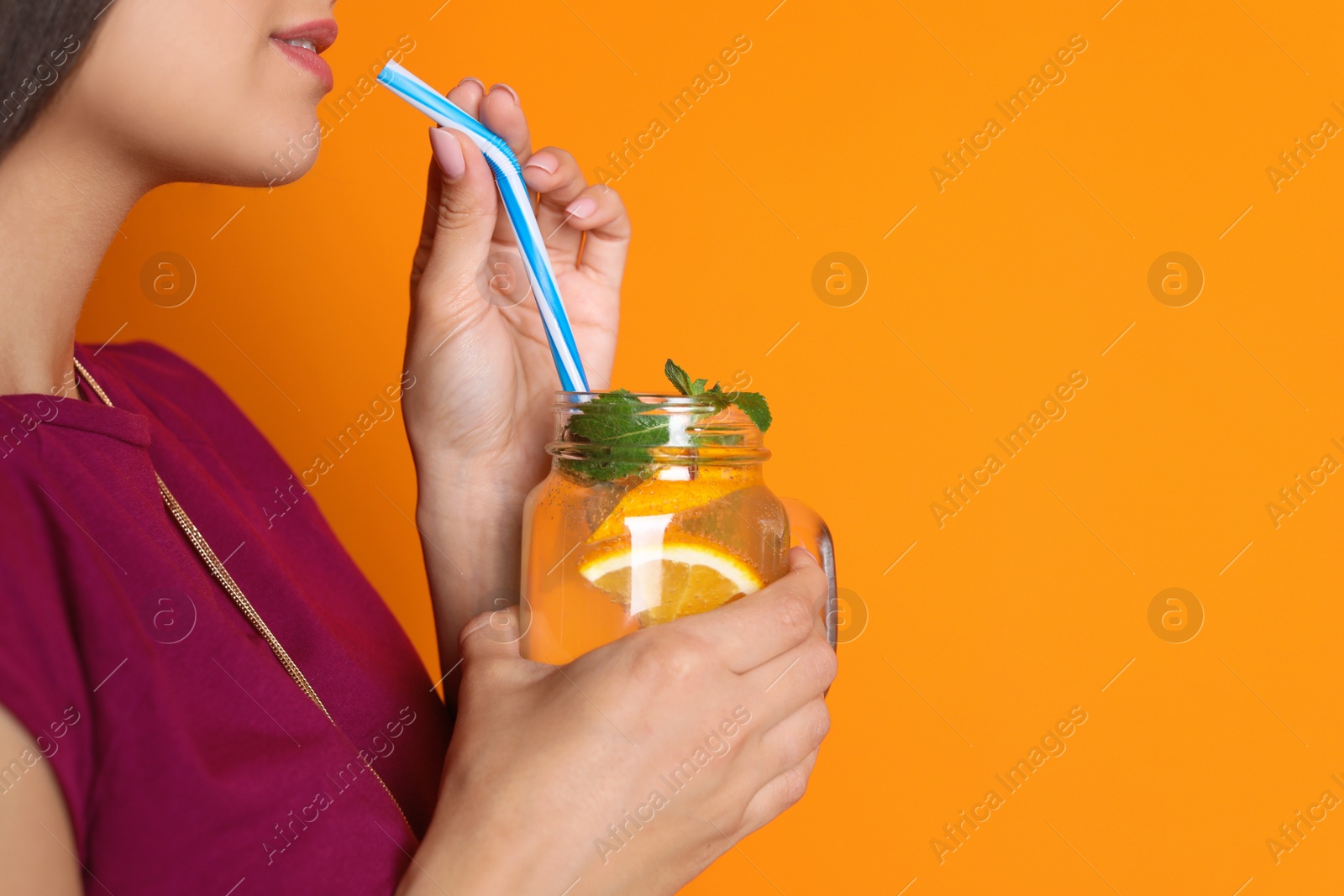 Photo of Young woman with mason jar of tasty lemonade on color background. Natural detox drink