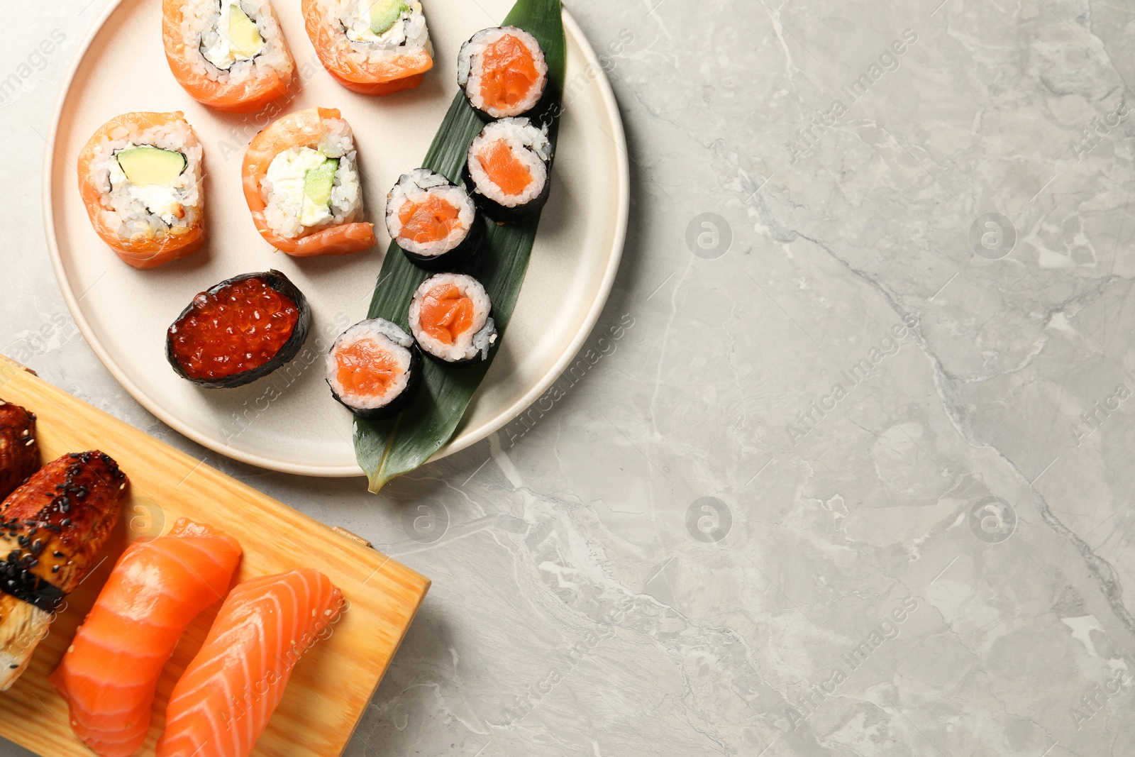 Photo of Delicious sushi rolls on light grey marble table, flat lay. Space for text