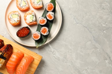 Delicious sushi rolls on light grey marble table, flat lay. Space for text