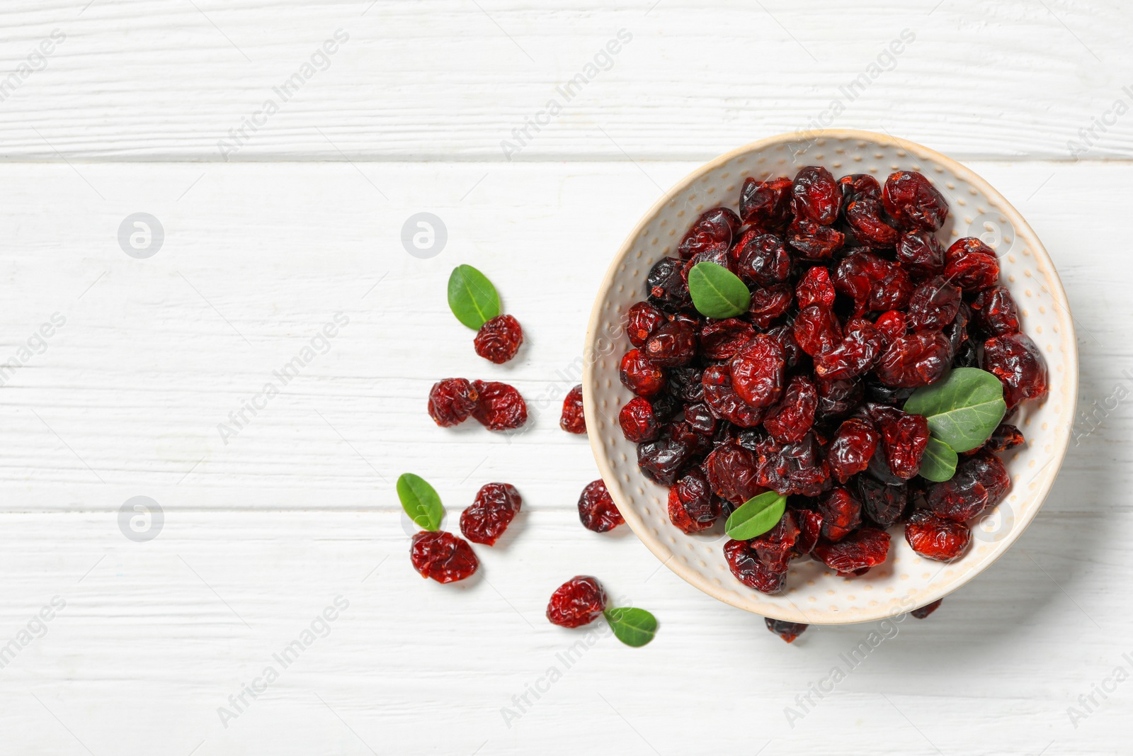 Photo of Flat lay composition with tasty dried cranberries and leaves on white wooden table. Space for text