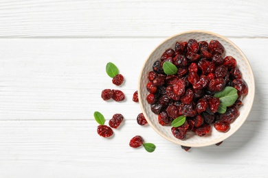 Flat lay composition with tasty dried cranberries and leaves on white wooden table. Space for text