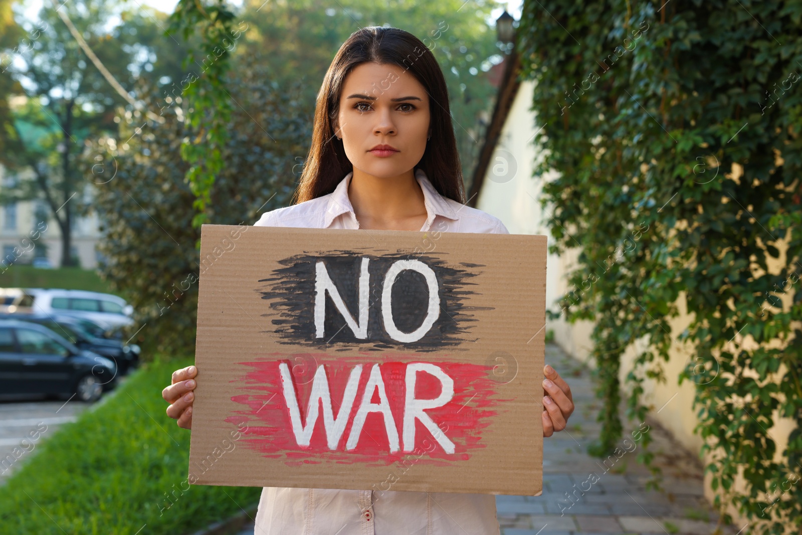 Photo of Sad woman holding poster with words No War on city street