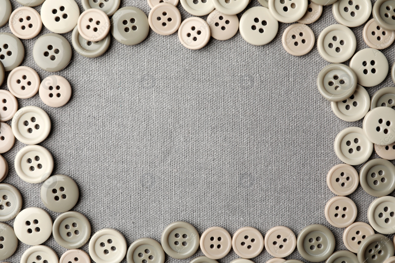 Photo of Frame of plastic sewing buttons on grey fabric, flat lay. Space for text