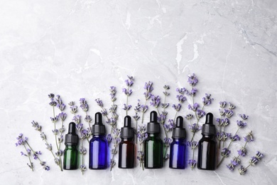 Photo of Flat lay composition with bottles of natural lavender essential oil on grey stone background. Space for text