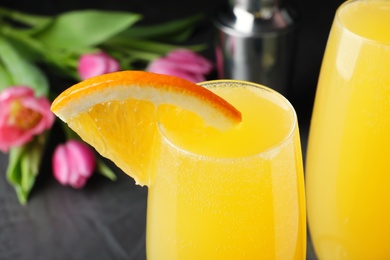 Photo of Glass of Mimosa cocktail with garnish on grey table, closeup