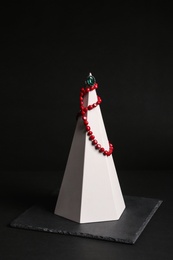 Photo of Elegant necklace and ring on stand against black background. Luxury jewelry