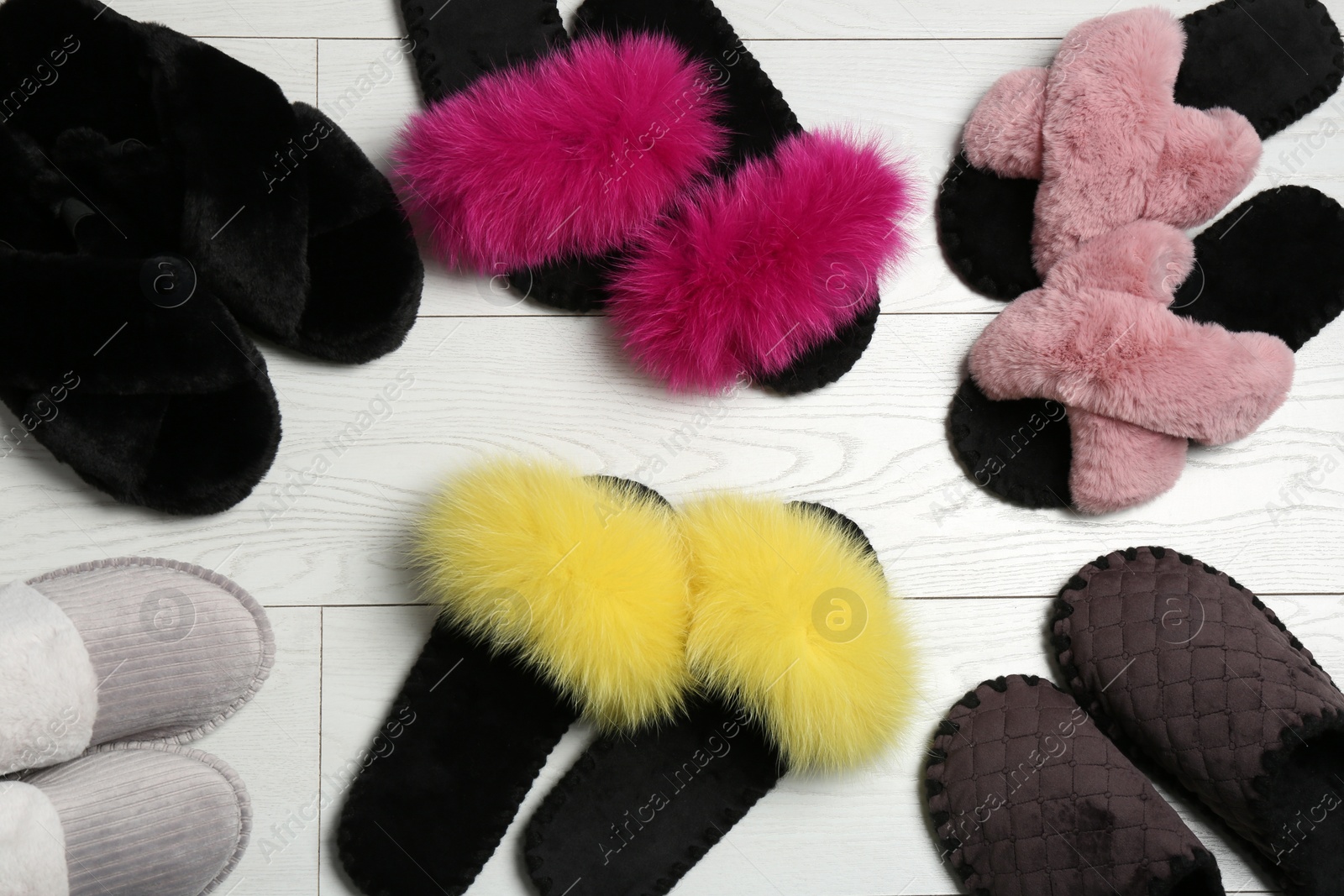 Photo of Many different soft slippers on white wooden background, flat lay