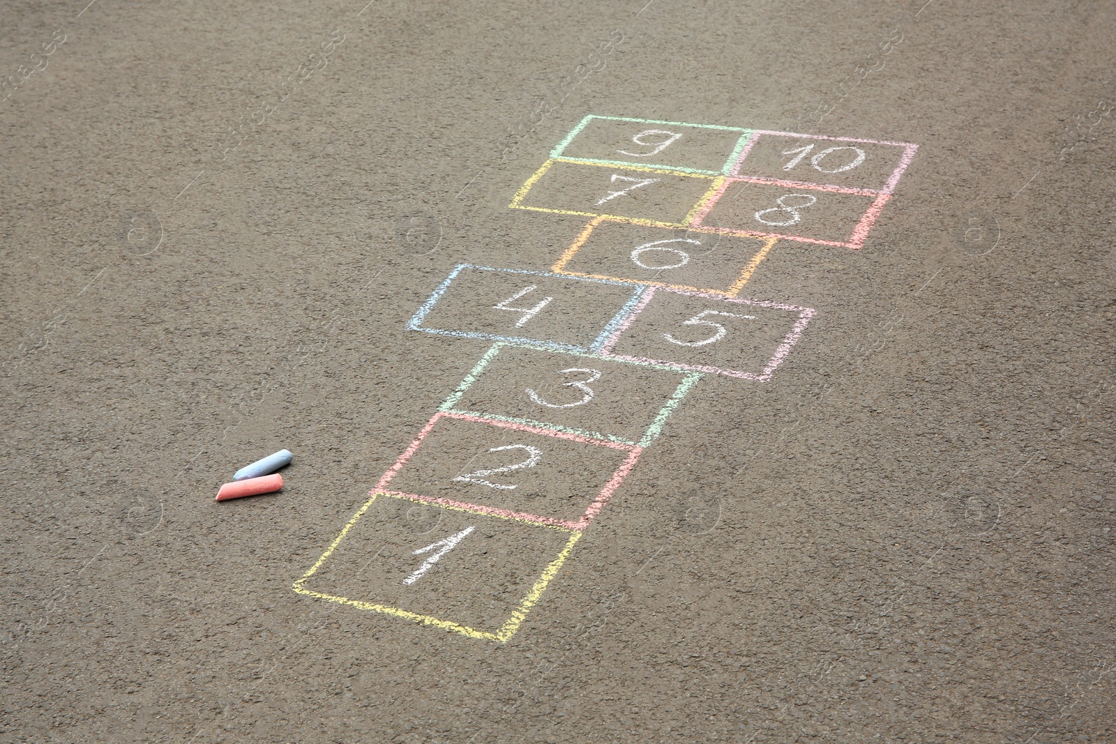 Photo of Hopscotch drawn with colorful chalk on asphalt outdoors